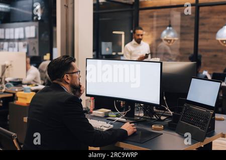 Manager using computer while working at desk in office Stock Photo