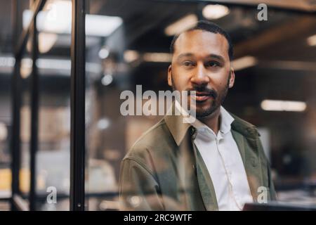 Thoughtful businessman standing in illuminated office Stock Photo