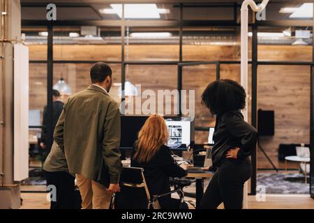 Colleagues discussing over computer at office Stock Photo