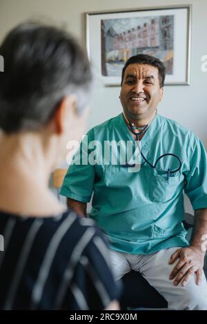 Happy male doctor with senior patient in clinic Stock Photo