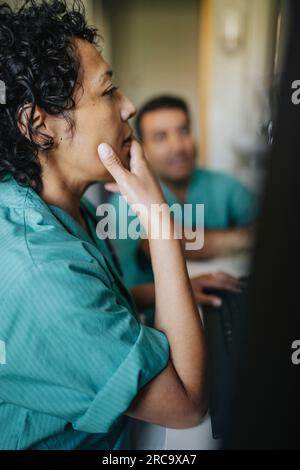 Female doctor with hand on chin using computer in hospital Stock Photo