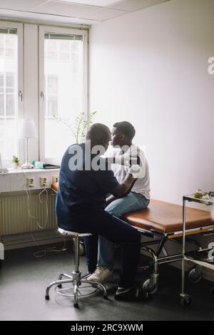 Mature male doctor giving vaccination to boy at hospital Stock Photo