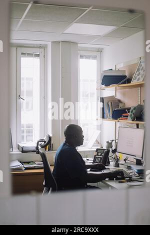 Mature male doctor working on computer at hospital Stock Photo