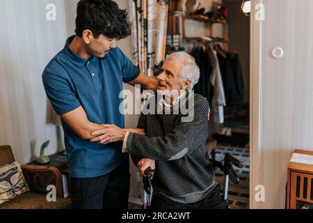 Senior man thanking male healthcare worker at home Stock Photo