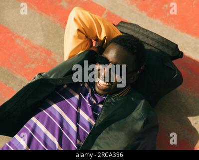 Carefree young man wearing sunglasses while lying on floor during sunny day Stock Photo