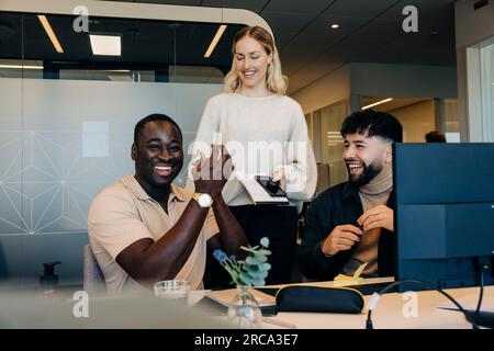 Happy businessman applauding with colleagues in coworking office Stock Photo