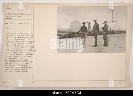 A theodolite instrument being used for testing wind velocity at different altitudes. The purpose is to accurately calculate the drift of shells fired from rifles. The picture shows a private holding a small rubber balloon that is released and tracked using the theodolite. The officer operating the instrument is 2nd Lt. Ivan R. Tannehill, S.C., and Private J.W. Strange holds the telephone receiver and transmitter to relay readings to the meteorological plotting room. Issued notes: 60740C. Stock Photo