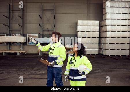 Female workers in protective workwear discussing at warehouse Stock Photo