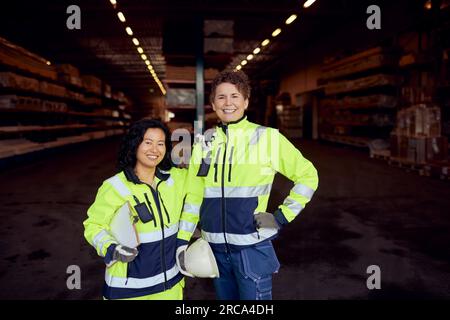 Portrait of smiling multiracial female coworkers in workwear standing in factory Stock Photo