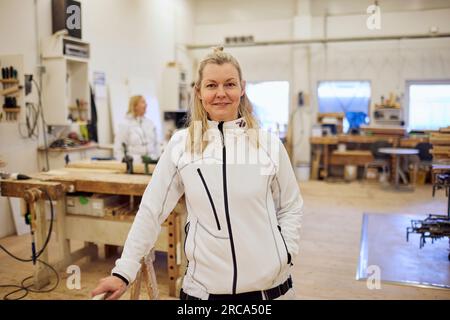 Portrait of smiling mature carpenter standing in workshop Stock Photo