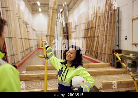 Smiling blue-collar worker discussing with colleague in lumber industry Stock Photo