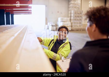 Smiling female worker discussing with colleague while working in lumber industry Stock Photo
