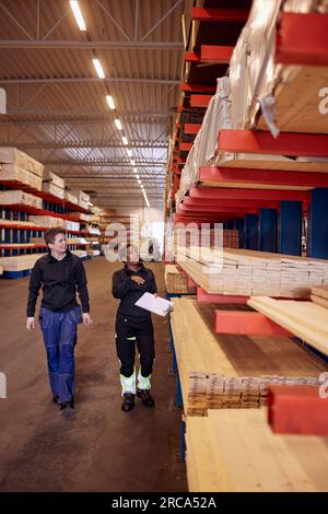 Full length of multiracial female workers examining planks on rack in lumber industry Stock Photo