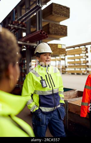 Female engineer with hands in pockets standing at lumber industry Stock Photo