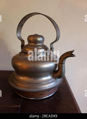 Antique bronze kettle stands on a dark-colored wooden table Stock Photo