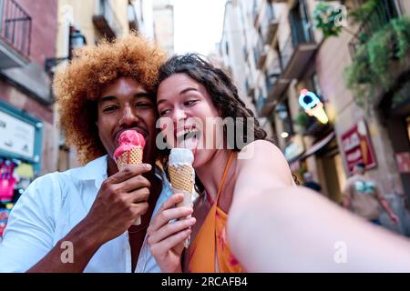 multiethnic couple of tourists taking selfie and eating ice cream Stock Photo