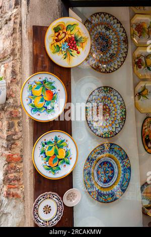 Siena, Italy - APR 7, 2022: Typical handicraft product, hand painted plates hanging on the wall of a souvenir shop in Siena, Tuscany, Italy. Stock Photo