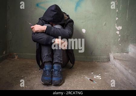 Addict in the hood of an abandoned house. The concept of drug abuse ...