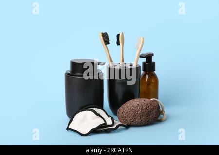 Holder with toothbrushes, bottle of cosmetic product, pumice and cotton pads on color background Stock Photo