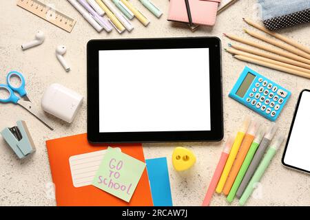 Sticky note with text GO TO SCHOOL, gadgets and different stationery on grunge white background Stock Photo