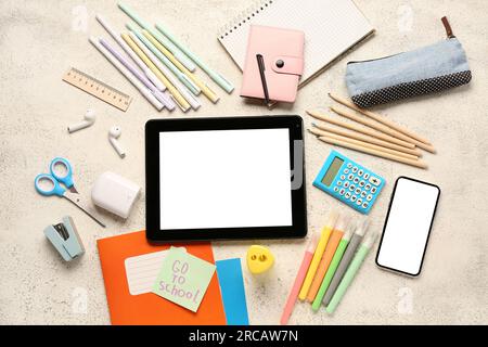 Sticky note with text GO TO SCHOOL, gadgets and different stationery on grunge white background Stock Photo