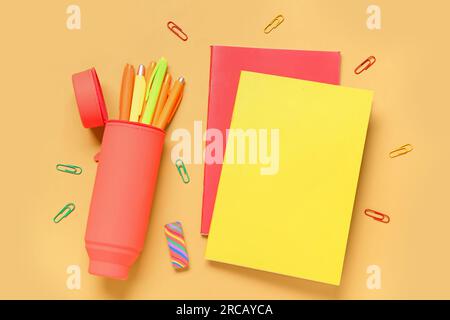 Case with pens and notebooks on orange background Stock Photo