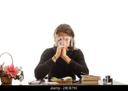 A young student sits at a table and thinks. Stock Photo