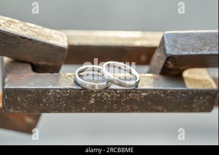Two hands with wedding rings rest on a strong anchor chain. Stock Photo
