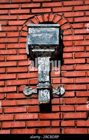 Partial drain pipe is mounted on the historic train depot in Strong City, Kansas.  Vintage pipe and cover has peeling paint and lower part of drain pi Stock Photo