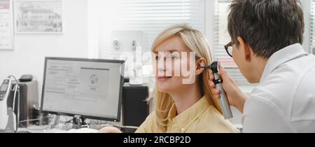 Woman patient having check-up of hearing at doctor otolaryngologist. Hearing exam for female. Otolaryngologist doctor checking mature woman's ear Stock Photo