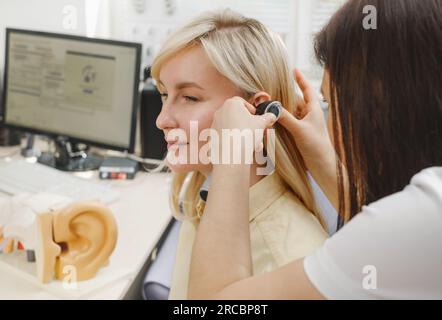 Woman patient having check-up of hearing at doctor otolaryngologist. Hearing exam for female. Otolaryngologist doctor checking mature woman's ear Stock Photo