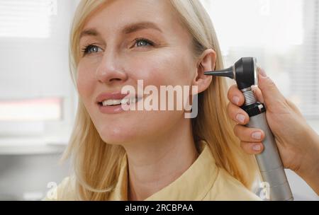 Woman patient having check-up of hearing at doctor otolaryngologist. Hearing exam for female. Otolaryngologist doctor checking mature woman's ear Stock Photo