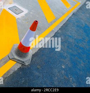 Red and white road marking cone on freshly painted parking lot. Stock Photo