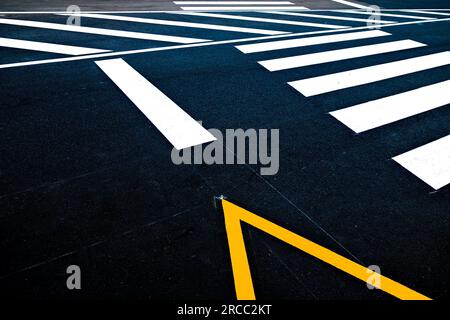 A zebra crossing and a parking lot signage on a black road, an abstract fragment of the pavement. Stock Photo