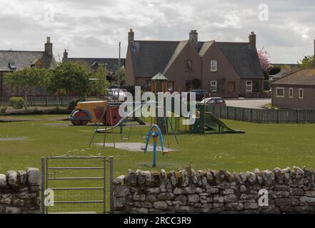 Scotland, UK - May 9th 2023 -  Looking at a childrens playground over a dry stone wall with no one around Stock Photo