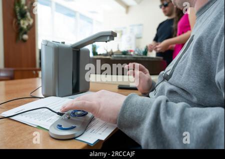 A visually impaired man uses a scanning and reading machine. Stock Photo