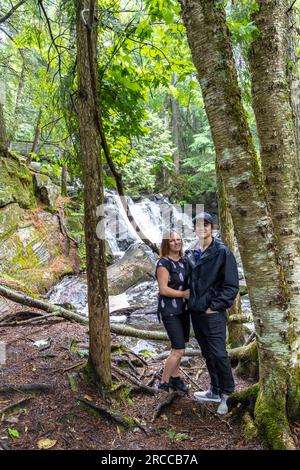 couple posing in front of waterfall in thick forest Stock Photo