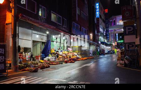 Busan, South Korea - March 19, 2018: Night street view with a food market, fruits and vegetables for sale Stock Photo