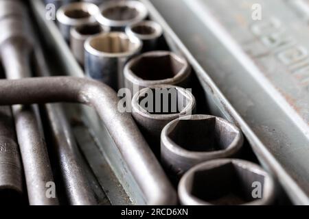 A close up portrait of multiple metal sockets of different sizes of a socket wrench in an open old metal toolbox, ready to be used by a skilled mechan Stock Photo