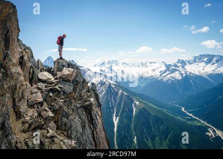 Male mountaineer standing on the edge of a cliff looking down, Canada Stock Photo