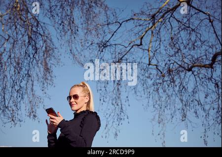 Attractive woman using smartphone in park Stock Photo