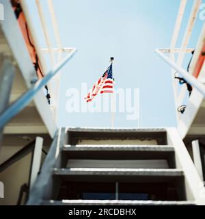 View from below deck on a boat, looking up stairs at an American flag Stock Photo