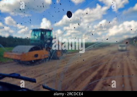 Dirty road after rain. Dirt highway with dirt flies on the windshield from other cars, dirty conditions for driver Stock Photo