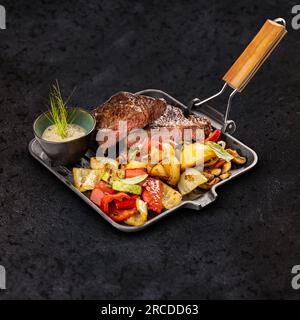 Grilled pork chops with roasted vegetables served with sauce in iron pan Stock Photo
