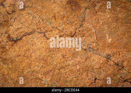 Old orange stonewall in closeup with cracks Stock Photo