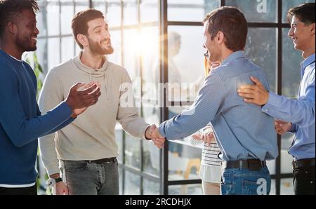Happy colleagues welcome businessman to their successful team Stock Photo
