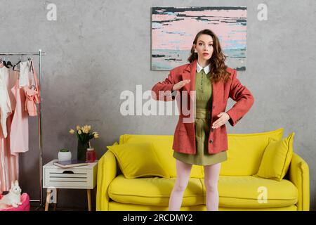 concept photography, woman acting like a doll, gesturing unnaturally and standing near yellow couch and wardrobe, well dressed and beautiful,  living Stock Photo