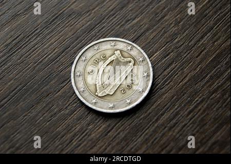 Used coin on a dark wooden table. Irish 2 euro coin. Stock Photo