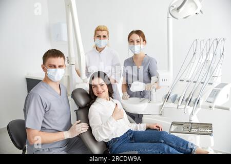 Team of professional dentists in uniform taking pictures and healing teeth of client during work in contemporary office of dental clinic Stock Photo