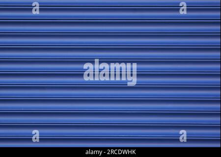 Roller blinds and garage gates. Closed metal shutter casements close-up. Background of blue horizontal metal strips with blue paint. Stock Photo